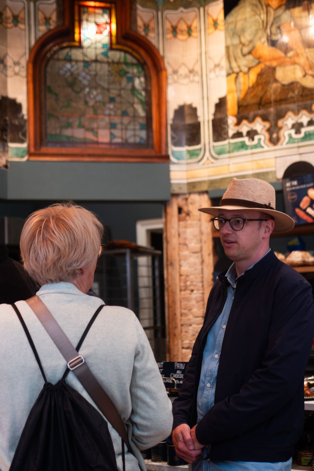 Jan talking with a guest inside a historic tiled Amsterdam shop interior