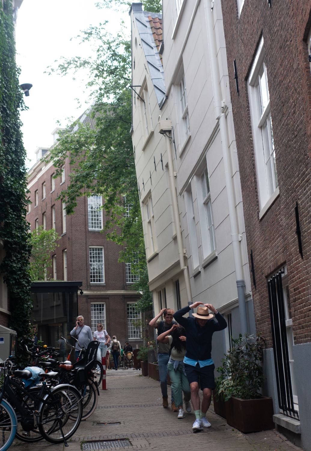 Guests walking a narrow lane between leaning houses in Amsterdam's old centre